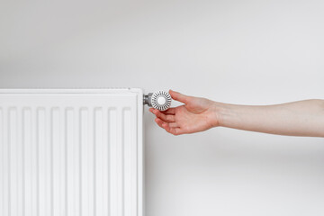 Woman adjusting thermostat on white heating radiator