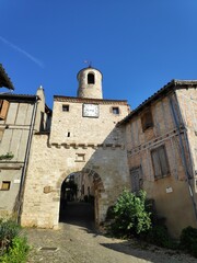 Fototapeta na wymiar Entrance door of a medieval village with a bell tower and a clock at Corde-sur-ciel in France