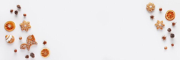 Christmas banner is made of Christmas gingerbread, nuts, cones, dried orange slices and anise stars on a white background. Copy space.