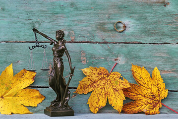 Haftung bei Unfällen mit Laub im Herbst. Justitia Figur mit Laublättern