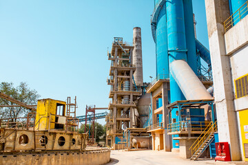 Fototapeta na wymiar Cement factory. Pipes and compressors, equipment, metalurgy. Modern technologies work at a cement plant. Technological work on the production of cement. Working atmosphere with copy space.
