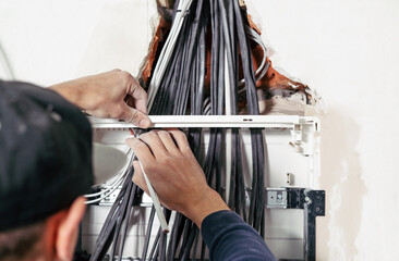Dangerous work with electricity. The electrician installs the electrical panel and prepares the...
