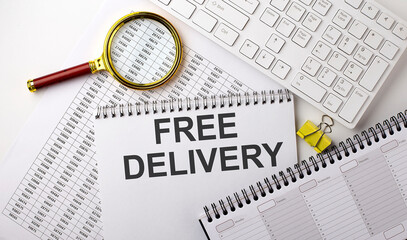 Fototapeta premium FREE DELIVERY text written on a notebook on chart with keyboard and planning
