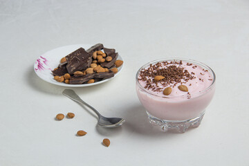 Yogurt with chocolate and almonds on a light background