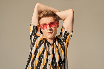 Obraz premium Red haired man in glasses holding his hands behind his head and posing fashionably