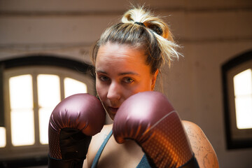 Portrait of young woman at boxing training session. Attractive woman in sport clothes standing at...