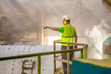 Working people at the cement plant are working signals to the shop for work. Technology work is the production of cement. Heavy male and female harmful to the environment and health work.