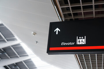 A sign with an arrow pointing to the elevator in the airport waiting terminal.