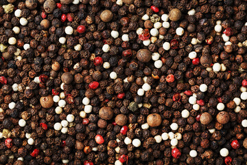 Seeds of a mixture of peppers with a texture on top in full screen. Black, white, green and pink pepper.