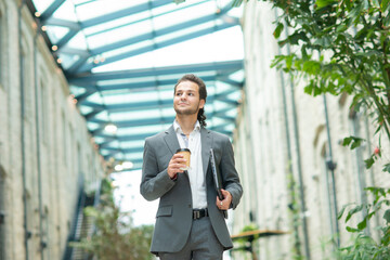 A young successful businessman is walking down the street. Man in a casual wear. Business, freelance and remote work.