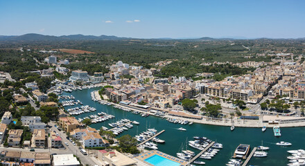 Naklejka premium Aerial view of the port and city of Porto Cristo on the Spanish Mediterranean island of Mallorca. It's summer with sunshine. The mountains can be seen in the background.