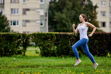 Fototapeta premium Graceful woman 29 years old in sportswear runs outdoors.