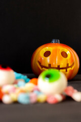 Scary orange pumpkin with delicious candies to celebrate Halloween, with a black background. Copy space, selective focus, concepts.
