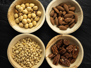 Hazelnuts, plain almonds, pine nuts, plain pecan kernels, background. Flat lay, top view.