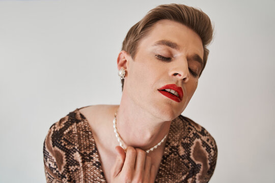 Womanlike man opened his mouth sensitively while posing at the female clothes