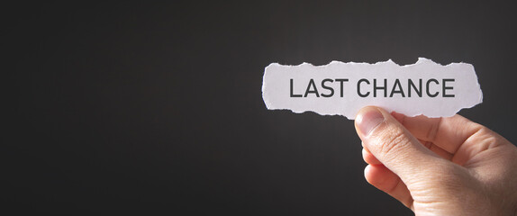 Male hand showing Last Chance message on torn paper.