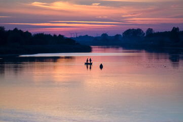Łódka wędkarze na rzece w pięknym oświetleniu zachodzącego słońca 
