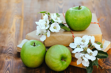 three green apples and flowers on a wooden background. harvest season