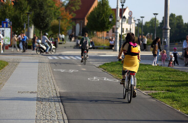 Młoda kobieta jedzie na rowerze po ścieżce rowerowej we Wrocławiu. - obrazy, fototapety, plakaty