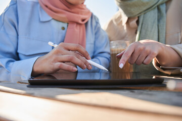 Two women in scarfs involved at the working with tablet