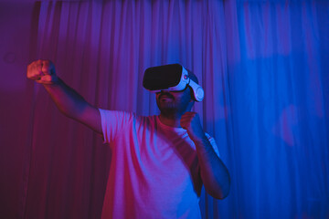 The man who entered the world of the metaverse with VR glasses is playing a boxing match. Young man having sporting fun in the virtual world.