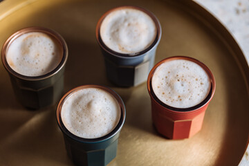 Macchiato in four different cups on a golden tray with golden spoon and cookies in jar 