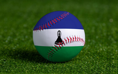 Baseball with Lesotho flag on green grass background, close up