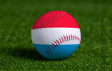 Baseball with Luxembourg flag on green grass background, close up