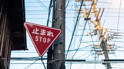 Red triangular stop warning traffic road sign with white letters kanji at Japan