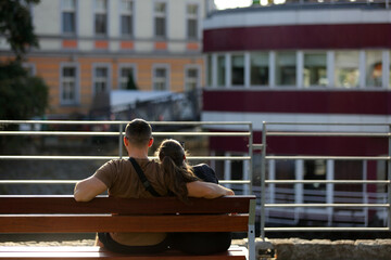 Para młodych ludzie wypoczywają, siedzą na ławce we Wrocławiu nad kanałem.