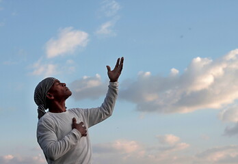 man praying to god with arms outstretched looking up to the sky stock photo	
