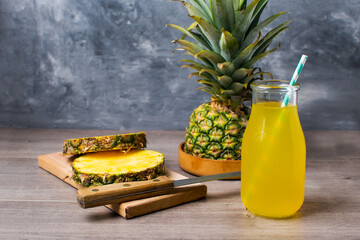 glass of pineapple juice. Side view on a wooden table and gray background