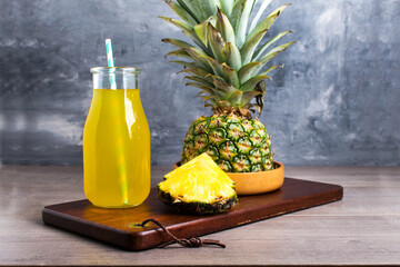 Fototapeta na wymiar glass of pineapple juice. Side view on a wooden table and gray background