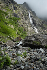 Majestic landscape Midagrabin waterfall in sunlight in cloudy summer weather. Caucasus mountains. Russia. North Ossetia Alania