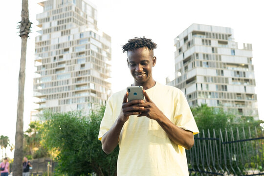 Cheerful young black man messaging on smartphone