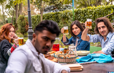 group of multi-cultural friends having fun at garden party - Young people smiling together eating food and drinking beer