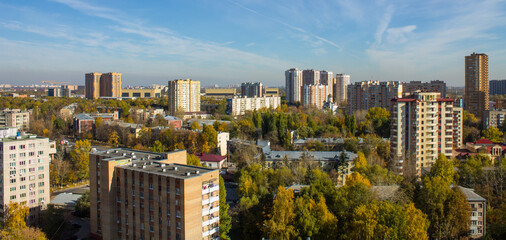 Panoramic top view of modern city houses among autumn trees with colorful foliage and blue sky on a clear October day. Concept urban landscape in Reutov, Moscow region and copy space