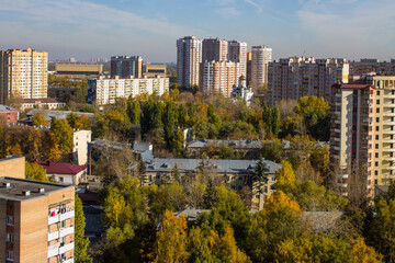 Fototapeta premium Panoramic top view of modern city houses among autumn trees with colorful foliage and blue sky on a clear October day. Concept urban landscape in Reutov, Moscow region and copy space