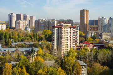 Fototapeta na wymiar Panoramic top view of modern city houses among autumn trees with colorful foliage and blue sky on a clear October day. Concept urban landscape in Reutov, Moscow region and copy space