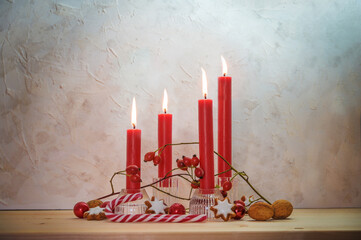 Four lit red candles for the fourth Sunday before Christmas, Advent decoration on a wooden table...