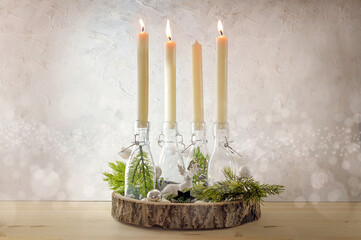 Creative Advent wreath, candles in bottles on a wooden board with fir branches and decoration...