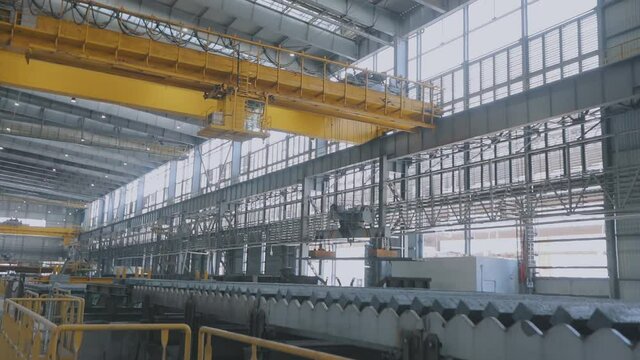 Yellow overhead crane with an electromagnet. A yellow bridge crane with an electromagnet moves hot metal. An overhead crane in a modern workshop.