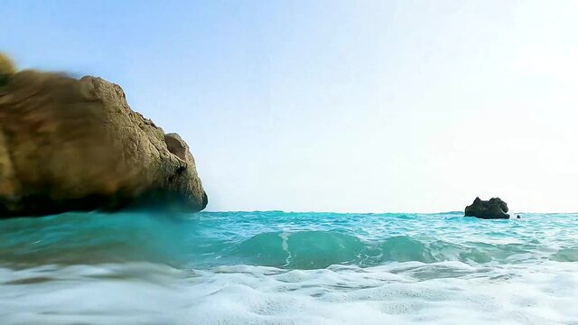 SMALL TURQUOISE OCEAN WAVES OVERSPASHING WITH CAMERA ON STONEBEACH 