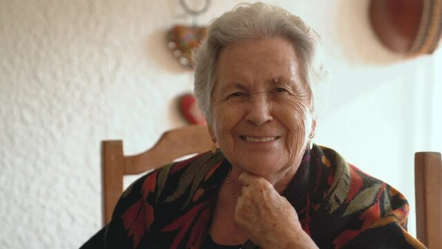 Senior smiling woman in warm shawl in dining room