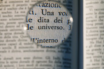 words from a book written in Italian enlarged by a magnifying glass