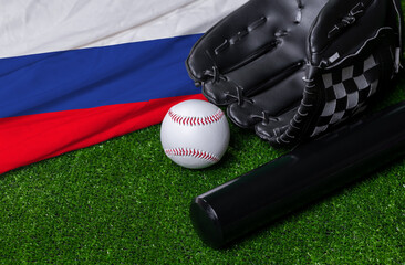 Baseball bat, glove and ball near Russia flag on green grass background