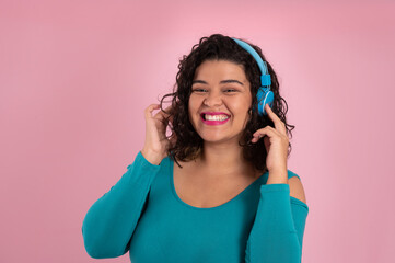 Fototapeta premium happy young woman smiling and looking to camera with headphones on pink background.