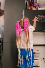 Colored  braids in a pink shade in a hairstyle on a blonde girl