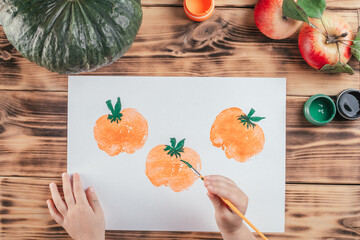 Step-by-step Halloween tutorial pumpkin apple prints. Step 9: Child hand draws tails to pumpkins...
