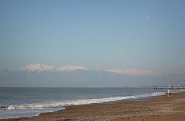 view from the coast to the sea and mountains with a walking man
